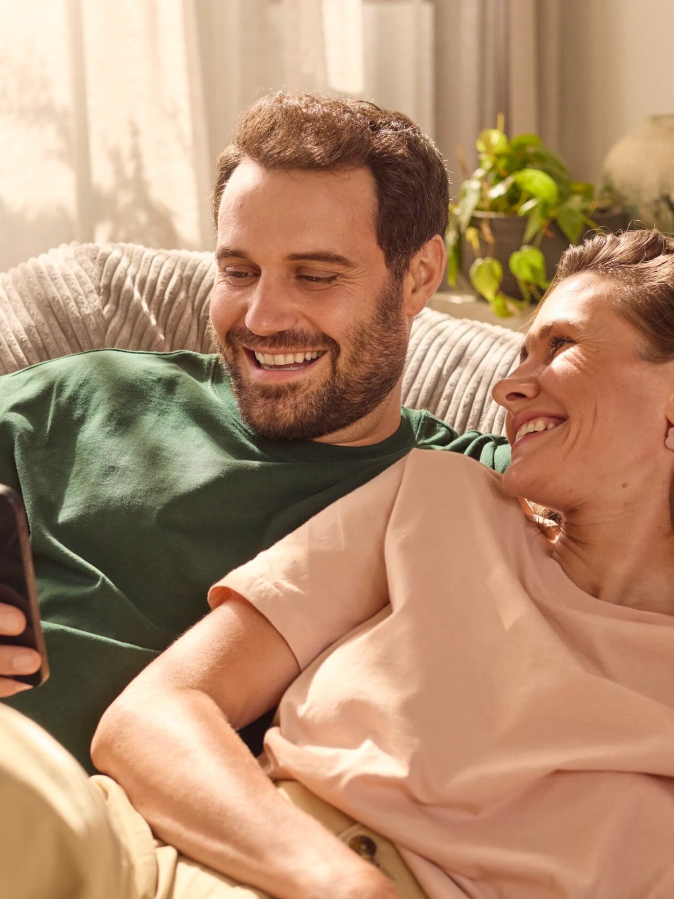Par sjedi na kauču i gleda u telefon